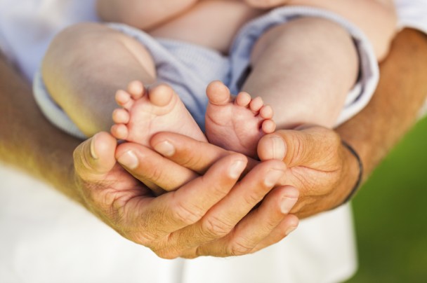 Father's Hands Holding Newborn's Feet